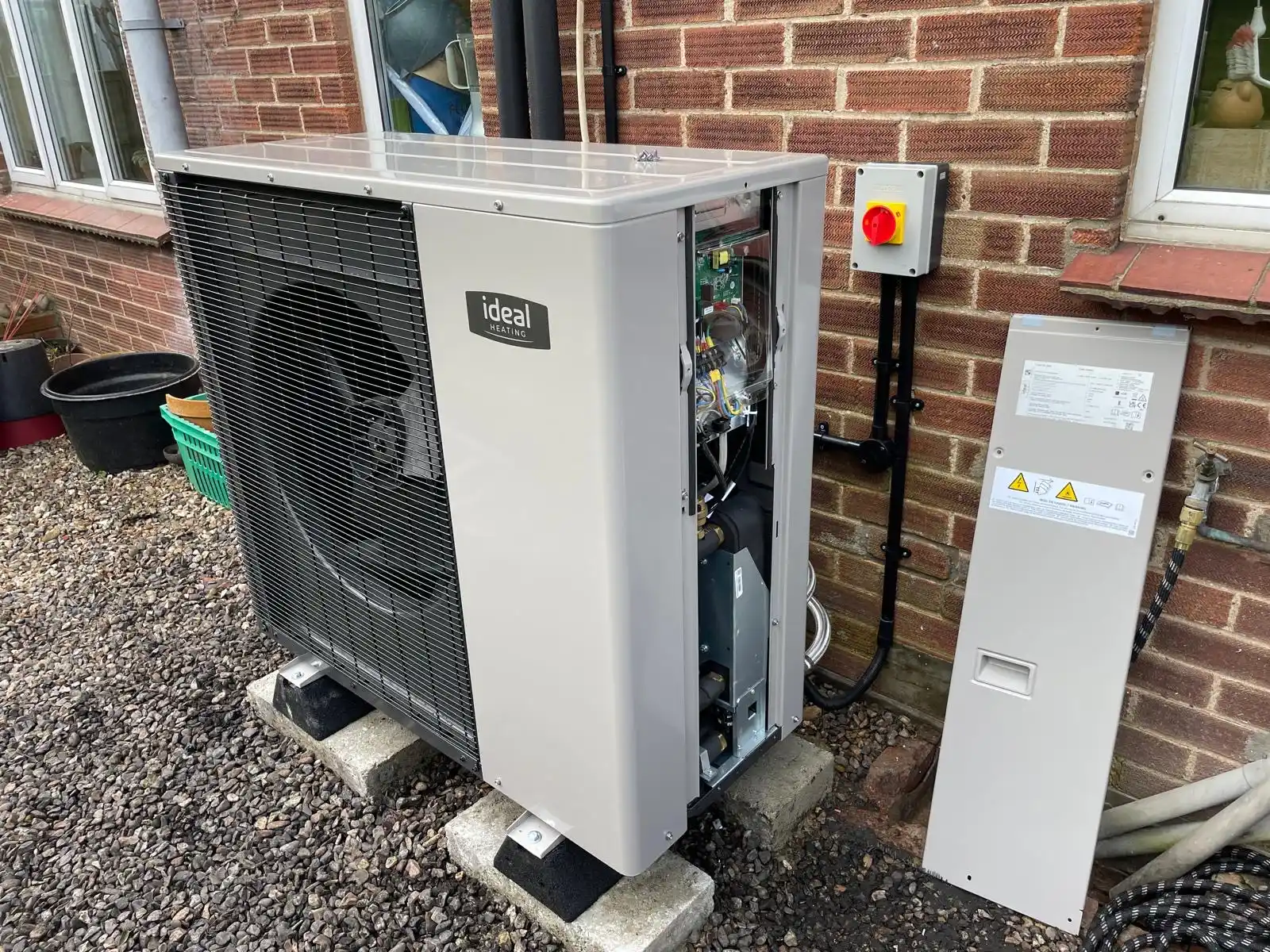 An Ideal Heating air source heat pump unit being installed against a brick wall – commercial renewable energy project installation